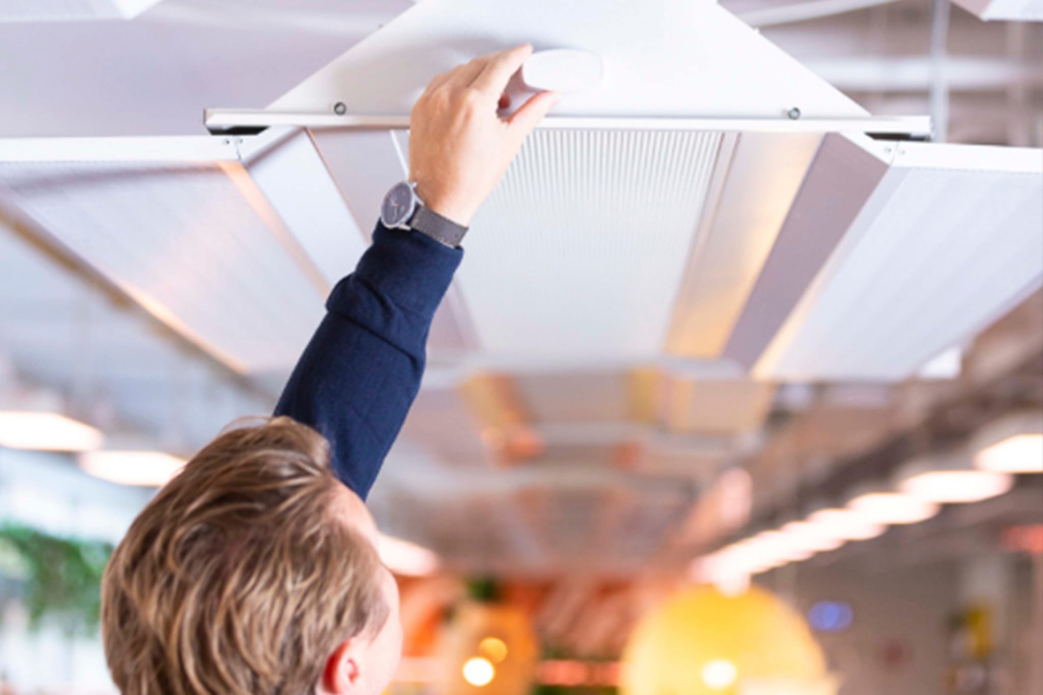 Man installing Flowscape's indoor positioning beacon in a modern office.