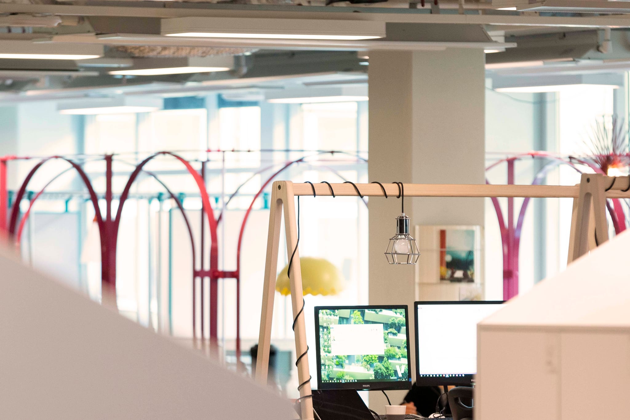 Picture of desk with two computer screens in an open and modern office environment.