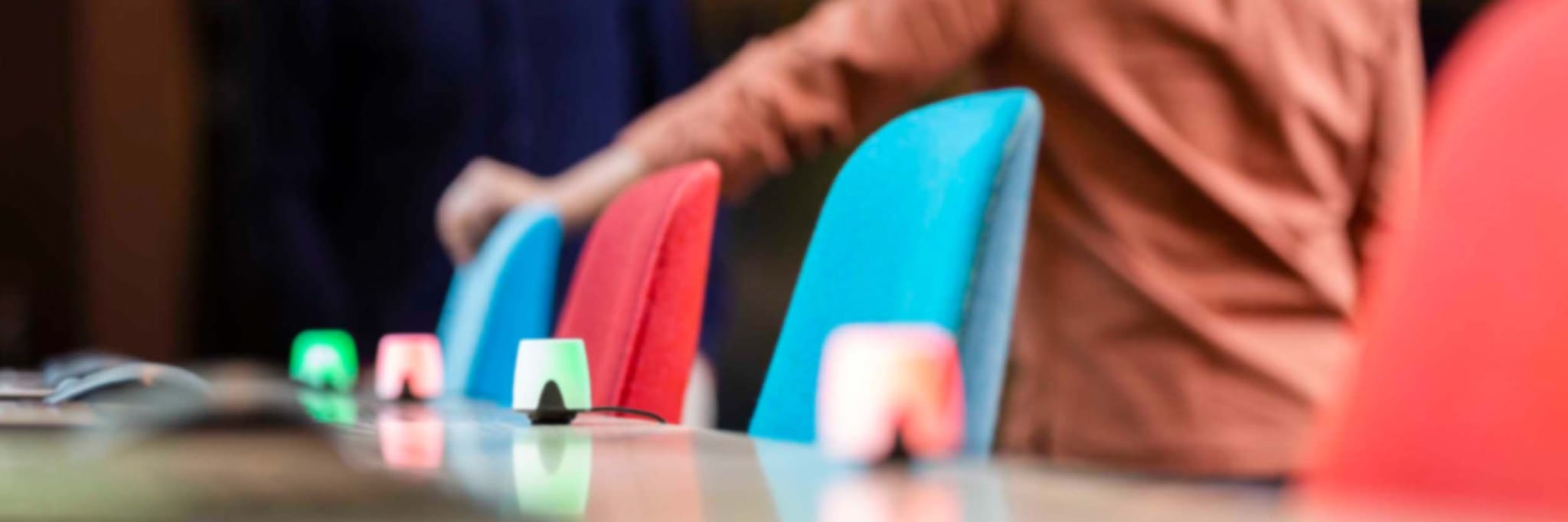Close-up of colorful office chairs with occupancy sensors displaying red and green lights, showcasing Flowscape’s smart hardware for real-time desk availability in a hybrid workplace.