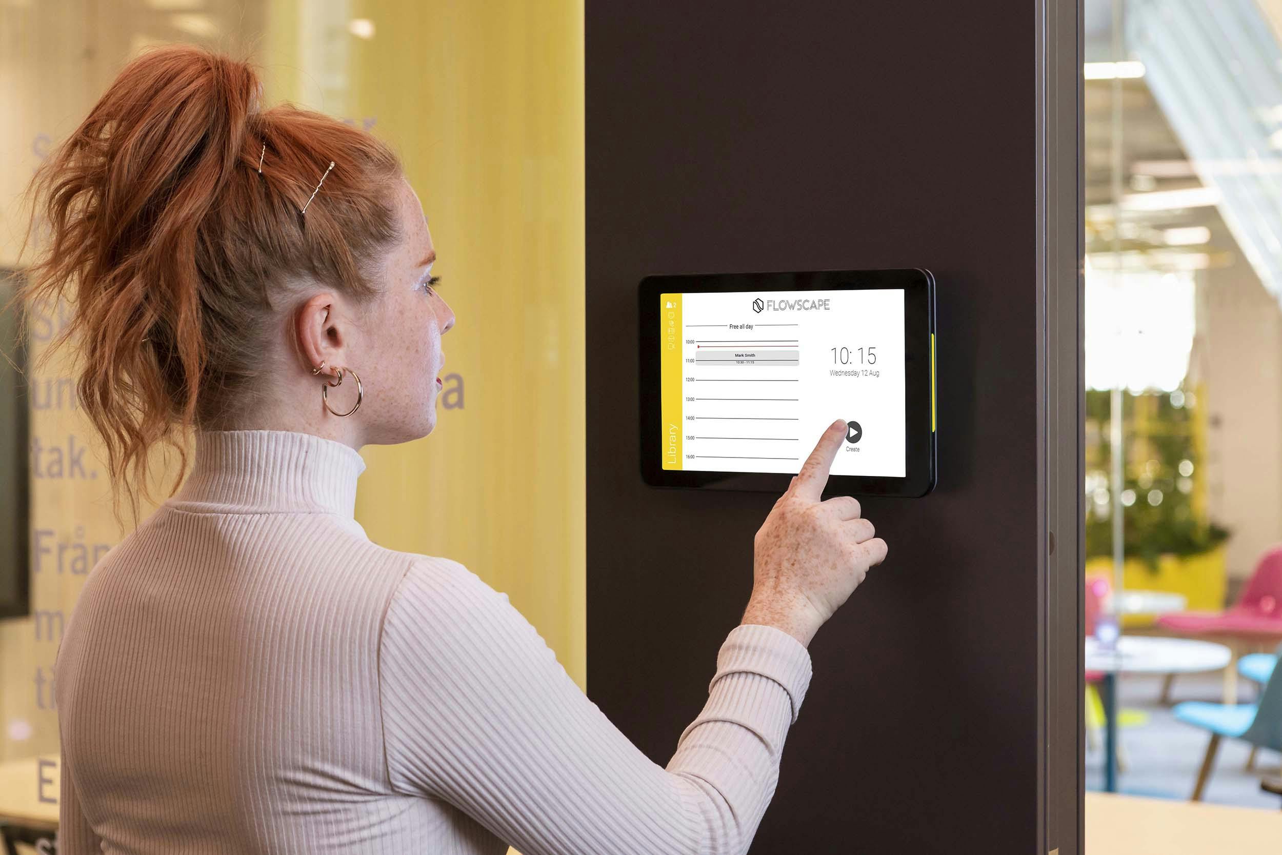 woman checking in to a conference room on a Philips room display