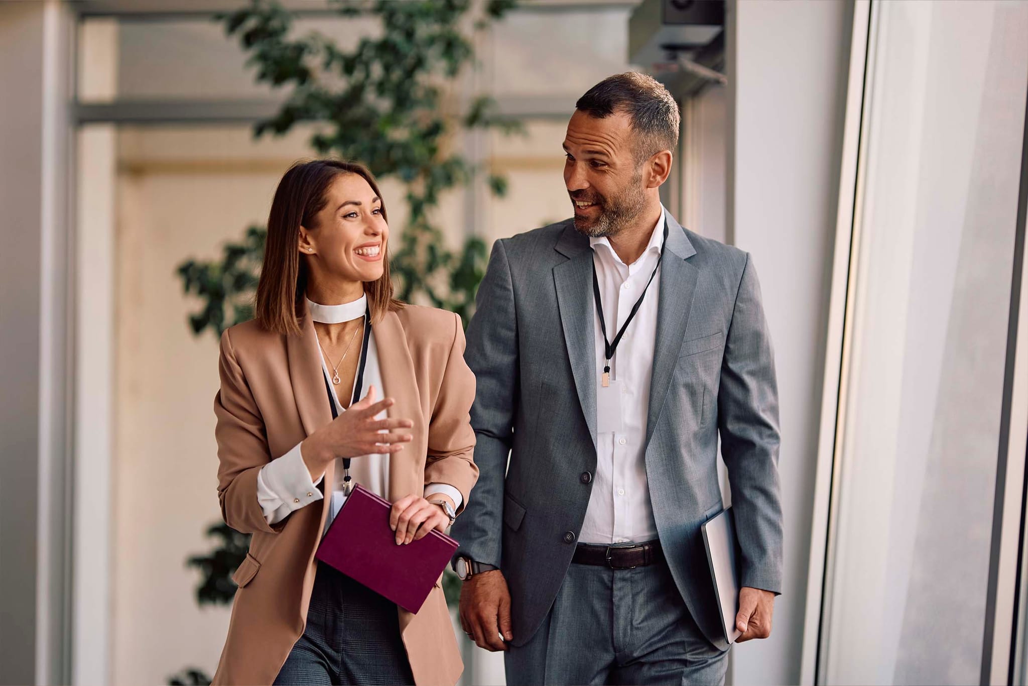 Two professionals walking and having a conversation in a modern office corridor, representing collaboration and mobility in a flexible hybrid workplace.